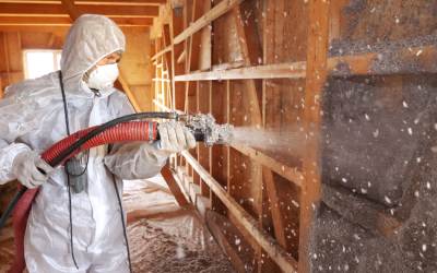 A worker blowing insulation into a wall.