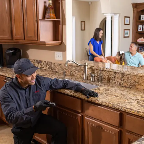 A pest control technician shines a flashlight in the kitchen of a Kansas home while inspecting for unwanted pests. Contact American Pest Management to eliminate unwanted pests from your home or business.